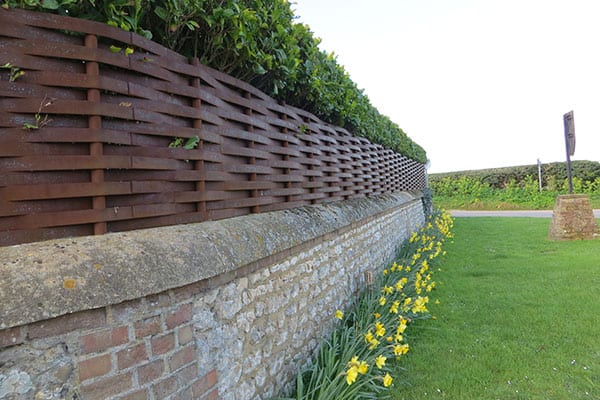 woven steel fence on top of wall